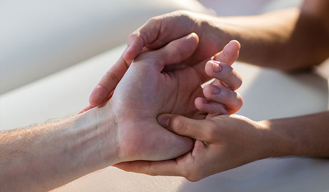 physiotherapist performing hand massage on patient