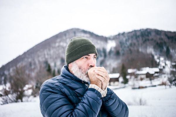 man outside rubbing his hands in the winter