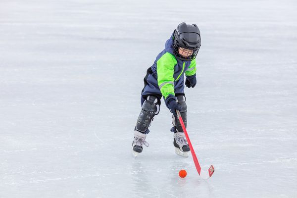 a child playing hockey outdoors alone 