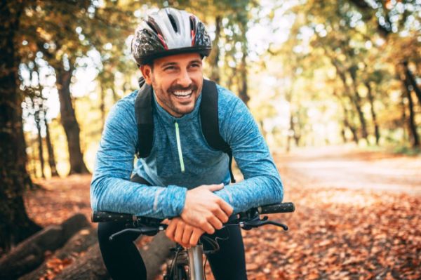 Happy man in blue cycling in autumn 