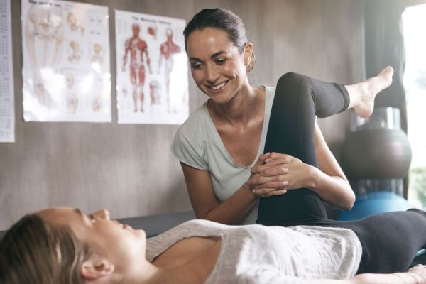 female physiotherapist assessing hip flexion of female patient