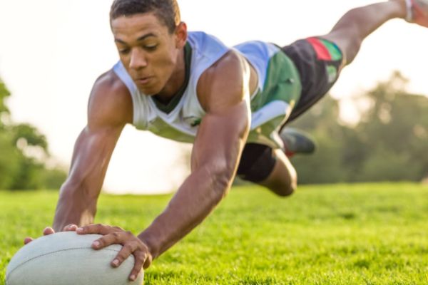 Young athlete falling on rugby ball