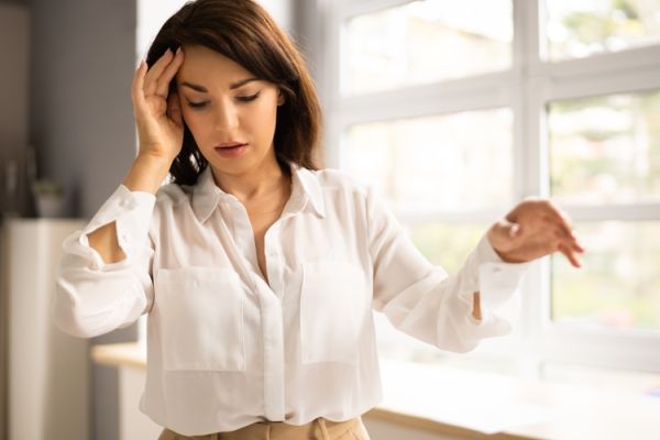 Women standing with hand on head feeling dizzy