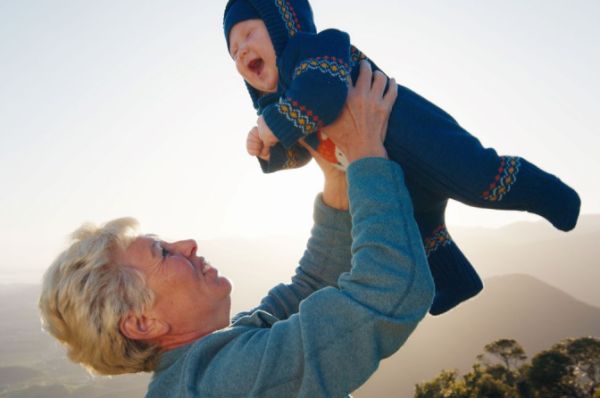 Grandmother holding toddler grandson up in the air