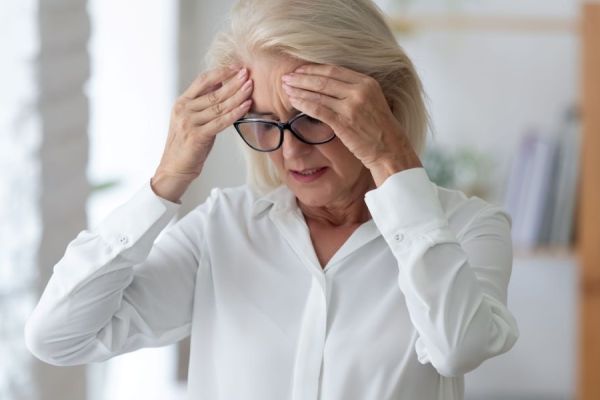 Woman with hands on head dizzy headache