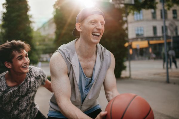 Two friends playing basketball outdoors 