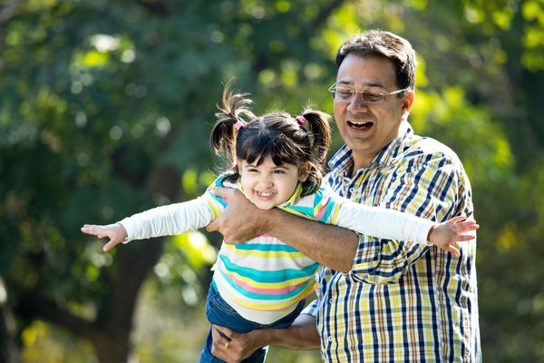 A man playing out doors with his daughter 