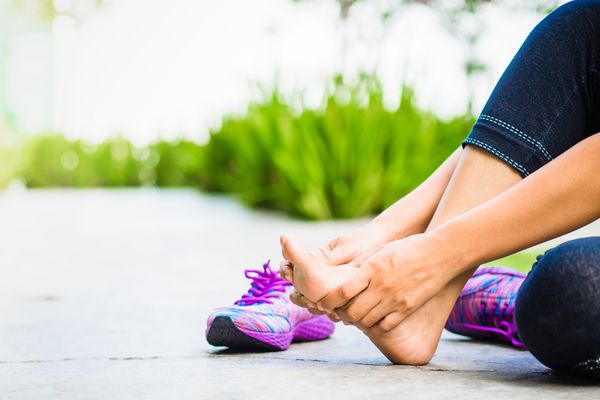 a woman rubbing her feet outdoors 