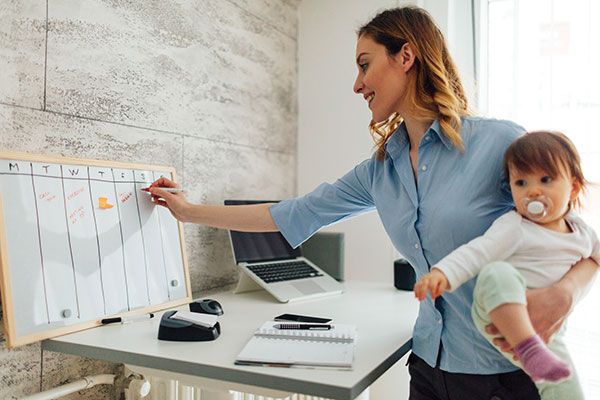 woman holding a baby and writing on a whiteboard