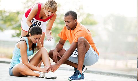 marathon racer sits on the ground with injured ankle