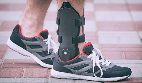 close up of man with ankle brace and athletic shoes