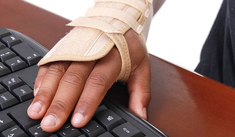 man with wrist splint using computer