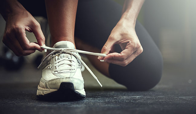 woman tying white athletic shoe