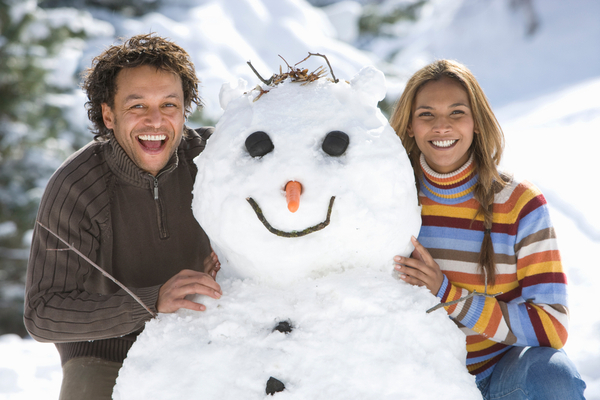 couple building snowman in the winter