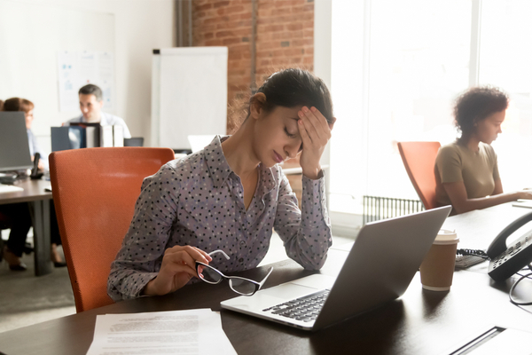 A woman suffering from a headache at her desk at work